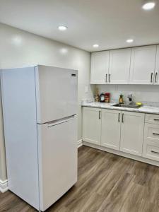 La cuisine est équipée de placards blancs et d'un réfrigérateur blanc. dans l'établissement Cozy Studio Bsmt in Scarborough Central, à Toronto