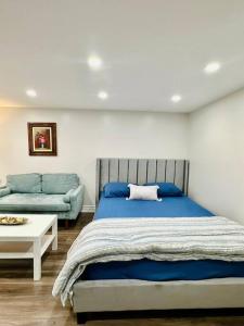 - une chambre avec un lit bleu et un canapé dans l'établissement Cozy Studio Bsmt in Scarborough Central, à Toronto