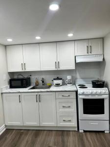 La cuisine est équipée de placards blancs et d'un four avec plaques de cuisson. dans l'établissement Cozy Studio Bsmt in Scarborough Central, à Toronto