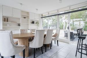 a dining room with a wooden table and white chairs at Uncover Mount Eliza's Charm from this Local Stay in Mount Eliza