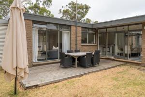 an outdoor deck with a table and chairs and an umbrella at Uncover Mount Eliza's Charm from this Local Stay in Mount Eliza