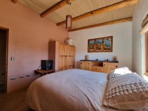 um quarto com uma cama e uma televisão em Casa Ohana San Pedro de Atacama em San Pedro de Atacama