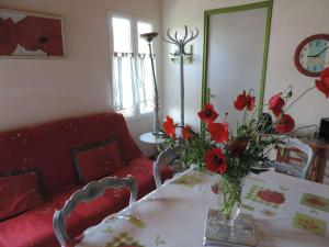 un vase de fleurs rouges sur une table avec un canapé rouge dans l'établissement Maison Noirmoutier-en-l'Île, 2 pièces, 4 personnes - FR-1-224B-214, à Noirmoutier-en-l'lle