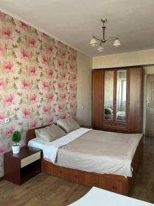 1 dormitorio con 1 cama grande con flores rosas en la pared en Квартира в Бишкеке, en Bishkek