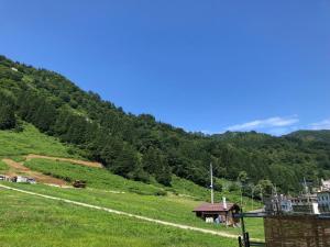 a grassy hill with a house and a road at TRAX NUNOBA - Vacation STAY 02612v in Yuzawa