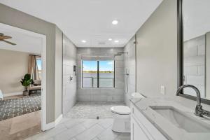 a white bathroom with a tub and a toilet at Experience breathtaking sunsets on Bluewater Bay! Private dock, 15 minute boat ride to Crab Island, 20 minute drive to Destin, Pet Friendly in Niceville