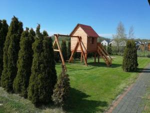 a wooden play structure in a yard next to trees at Ferienhaus in Rusinowo mit Großer Terrasse - b54244 in Rusinowo
