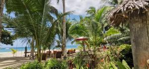 einen Strand mit einem Tisch, Stühlen und Palmen in der Unterkunft Sulu Sunset Beach Resort in Nauhang