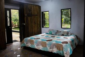 a bedroom with a bed and two windows at ¡Casa rústica con cabaña! Montaña, río, niebla, sol! 