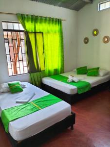 2 Betten in einem Zimmer mit grünen Vorhängen in der Unterkunft LUNA del DESIERTO TATACOA in Villavieja