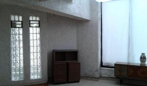 a living room with a tv and two windows at Agradable hogar en Playas de Tijuana in Tijuana