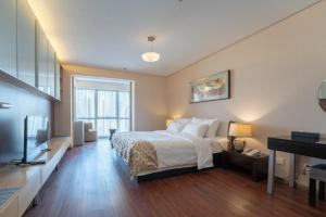 a large bedroom with a bed and a television at Qingdao Housing International Hotel in Qingdao