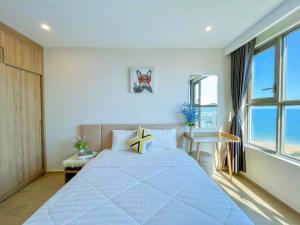 - une chambre avec un grand lit et une grande fenêtre dans l'établissement CĂN HỘ 5 SAO THE SÓNG VŨNG TÀU Mr VƯƠNG, à Vung Tau