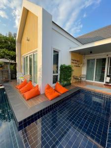 a swimming pool with orange pillows next to a house at Pool Villa Udonthani in Udon Thani