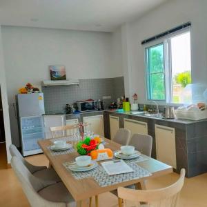 a kitchen with a wooden table with chairs and a dining room at Pool Villa Udonthani in Udon Thani