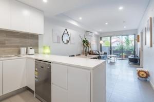 Una cocina con gabinetes blancos y una sala de estar. en 1Bedroom and Study Apt in Homebush Sleeps 5, en Sídney