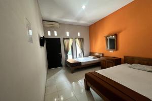 um quarto com 2 camas e uma parede laranja em HOTEL WARTA SARI em Denpasar