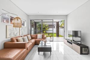 a living room with a brown couch and a tv at Lovely 4 Bedroom 3 Bathroom Modern Home Sleeps 8 in Revesby
