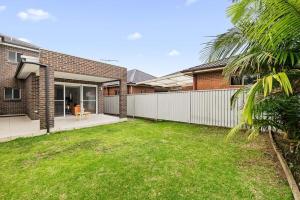 a backyard of a house with a fence at Lovely 4 Bedroom 3 Bathroom Modern Home Sleeps 8 in Revesby
