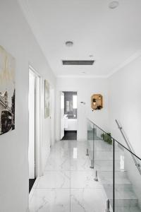 a hallway with white walls and a staircase with glass railings at Lovely 4 Bedroom 3 Bathroom Modern Home Sleeps 8 in Revesby