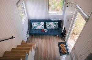 - un canapé bleu avec des oreillers dans une petite maison dans l'établissement Quiet Lake House In Winery, à Flowerdale