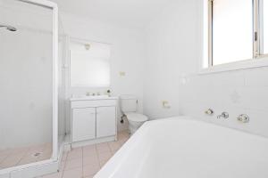 a white bathroom with a toilet and a shower at 3 Bdrms Duplex in Greystanes in Merrylands