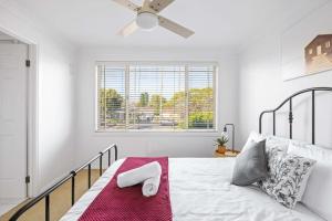 a white bedroom with a bed with a ceiling fan at 3 Bdrms Duplex in Greystanes in Merrylands