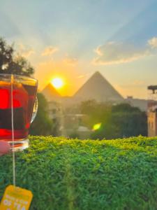 a glass of tea with the pyramids in the background at King pyramids view inn in Cairo