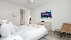 ein weißes Schlafzimmer mit einem Bett und einem Stuhl in der Unterkunft PGA208 Brand New PGA West 2 Bed 2 Bath w Loft in La Quinta