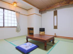 a living room with a table and a bench at 雀の宿 やぐら in Matsumoto