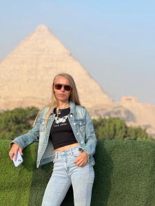 a woman is standing in front of a pyramid at King pyramids view inn in Cairo