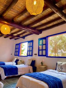 1 dormitorio con 3 camas con sábanas azules y blancas en Oceanside Surf & salsa, en Aourir