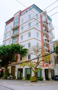 een hoog wit gebouw met een boom ervoor bij Bảo Hưng Hotel in Thanh Hóa