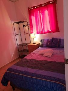 Dormitorio con cama morada y ventana rosa en Figueroa's House., en Santa Ana