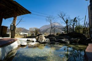 Yufuin Hotel Shuhokan في يوفو: تجمع مياه مع جبل في الخلف