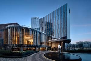 un grand bâtiment en verre avec une fontaine devant lui dans l'établissement Grand Barony Jinan CBD, à Jinan