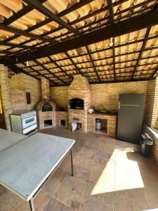 een grote kamer met een tafel en een bakstenen oven bij Chácara em Ibiúna com piscina e vista incrível in Ibiúna