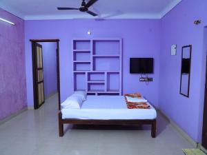 een paarse slaapkamer met een bed en een televisie bij La nest residency in Pondicherry