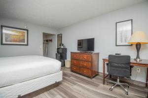 a hotel room with a bed and a desk and a television at Tremont Lodge & Resort in Townsend
