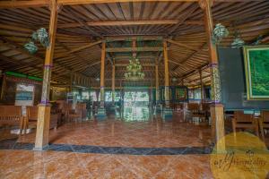 ein großes Zimmer mit Tischen, Stühlen und einem Kronleuchter in der Unterkunft Joglo Garut Cottage Syariah by My Hospitality in Bojongsalam