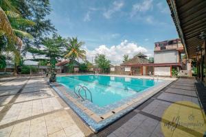 une piscine dans un complexe avec des arbres et un bâtiment dans l'établissement Joglo Garut Cottage Syariah by My Hospitality, à Bojongsalam