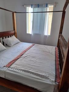ein großes Bett in einem Zimmer mit Fenster in der Unterkunft Cool breeze in Ukunda