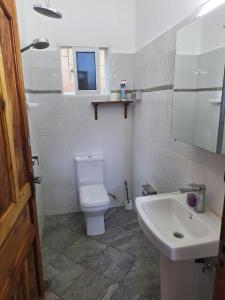 Łazienka z białą toaletą i umywalką w obiekcie Cool breeze w mieście Ukunda