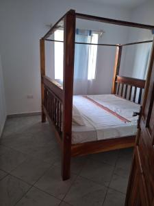 ein Etagenbett aus Holz in einem Zimmer mit Fenster in der Unterkunft Cool breeze in Ukunda