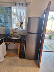 eine Küche mit einem Kühlschrank aus Edelstahl neben einer Spüle in der Unterkunft Cool breeze in Ukunda