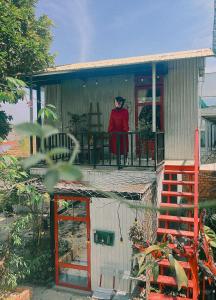 a woman standing on the balcony of a house at Utopia Homestay Đà Lạt in Khu Chi Lăng