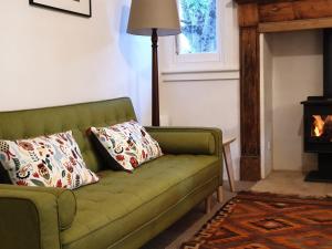 a green couch in a living room with a fireplace at Redruth - 2 bedroom cottage situated in wandiligong in Wandiligong
