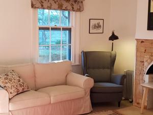 un salon avec un canapé et une chaise dans l'établissement Redruth - 2 bedroom cottage situated in wandiligong, à Wandiligong