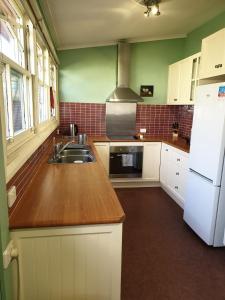 a kitchen with a sink and a white refrigerator at Redruth - 2 bedroom cottage situated in wandiligong in Wandiligong