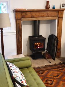 a living room with a fireplace and a green couch at Redruth - 2 bedroom cottage situated in wandiligong in Wandiligong
